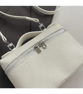 Top view of white lychee leather handbag with silver double zippers and smooth texture