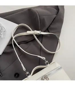 Detail of adjustable strap and silver metal buckle on a white lychee leather bag