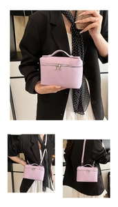 Detail of lavender litchi pattern handbag with silver zippers and removable strap