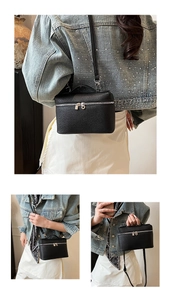 Detail view of black pebble leather lunchbox bag with silver zippers and adjustable strap