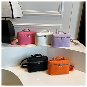 Five colored leather mini handbags displayed on a white minimalist pedestal with a lamp