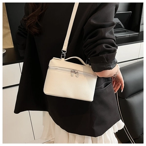 Detail of white lychee leather handbag showing silver hardware and crossbody strap
