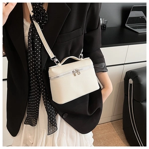 Close-up of white lychee pattern leather box bag with silver zippers and thin strap