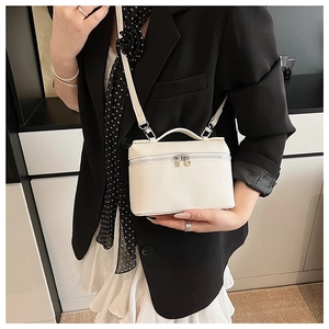 Detail of white lychee leather handbag with silver zippers and adjustable strap