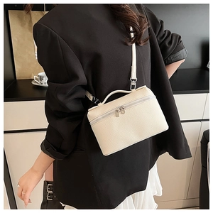 Close-up of beige lychee grain leather crossbody bag styled with a professional outfit