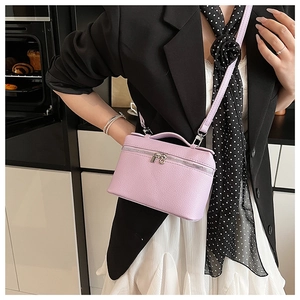 Detailed view of light purple pebble leather crossbody bag with dual zipper and handle