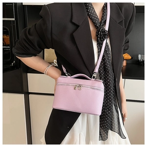 Detail of lavender textured leather crossbody bag styled with a professional black blazer