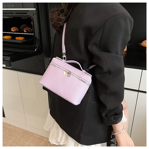 Detail of light purple textured leather box bag with zipper and top handle on a person