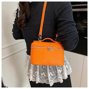 Bright orange pebble leather box bag shown as a crossbody on a stylish model