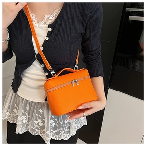 Detail of orange lychee textured leather mini handbag with dual zipper and top handle