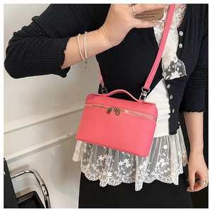 Detailed close-up of a pink lychee grain leather crossbody box bag with dual metal zippers