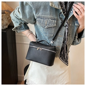 Detail of black pebbled leather crossbody bag featuring top handle and metal zipper