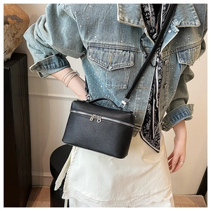 Detail of black lychee grain leather crossbody bag with silver hardware and top handle