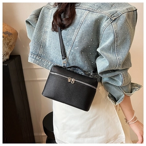 Close-up of black lychee grain leather crossbody bag with silver double metal zippers