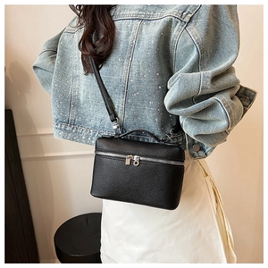 Close-up of black lychee grain leather crossbody bag with silver hardware and shoulder strap