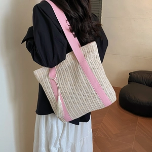 Grand sac fourre-tout en paille avec bandoulières en toile rose et gland sur modèle