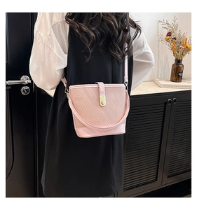 Pink bucket bag with wave woven texture and gold metal lock shown in a lifestyle setting