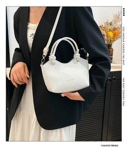 Detail of white lychee-patterned leather bucket bag with gold lettering and handles