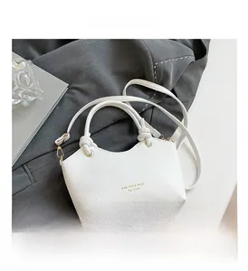 Close-up of white pebble grain bucket bag with unique knotted handle and gold hardware