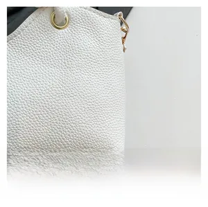 Detailed close-up of white pebbled leather texture and gold eyelet hardware on tote bag