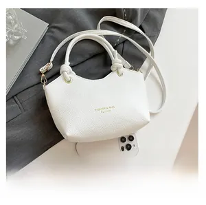 Detailed macro of white litchi pattern bucket bag with double arch handles and gold lettering
