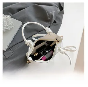 Interior view of white bucket bag showing capacity for phone, lipstick, and perfume