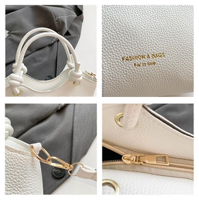 Detail view of white lychee leather texture, knot handle and gold metal hardware on handbag