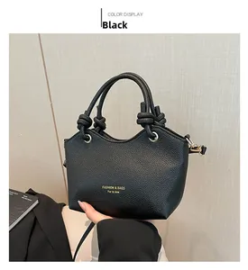 Detailed close-up of black lychee grain tote bag with knot handle and golden metal rings
