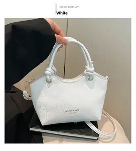 Detail of white lychee leather texture and knotted handle on a minimalist tote bag