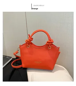 Detail of orange bucket bag featuring a knotted handle and lychee textured leather