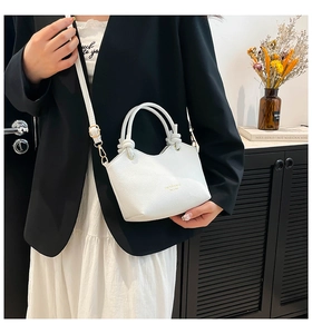 Close-up of white lychee pattern leather bucket bag with gold hardware and knot handle