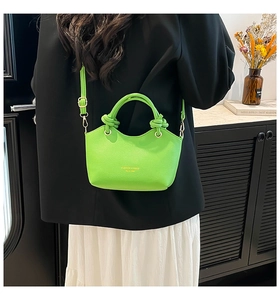 Detail view of neon green lychee grain leather bucket bag with knotted handle detail