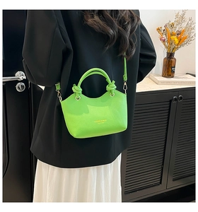Detail of bright green bucket bag featuring a knot handle and golden metal clasp accents