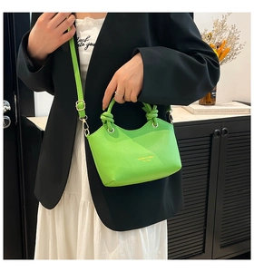 Detail of green tote bag featuring a knotted handle, gold hardware and fashion lettering