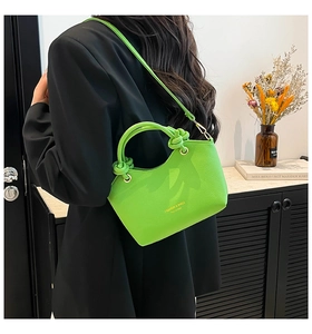 Detail of neon green bucket bag with pebbled leather texture and golden lettering