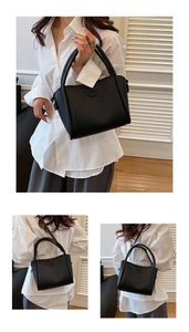 Detail of black lychee grain leather handbag with adjustable strap and top handles