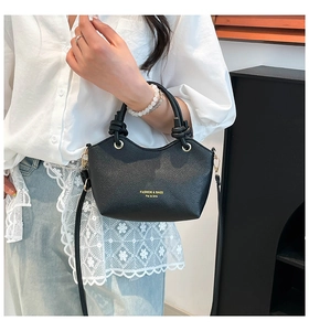 Detail of black pebbled leather tote bag with knotted handle and gold text