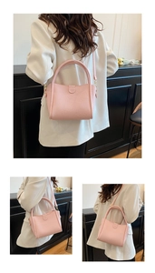 Detail view of pink pebble grain leather bucket bag with top handle and logo embossing
