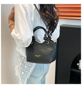 Detail of black lychee grain leather tote bag with knot handle and gold hardware
