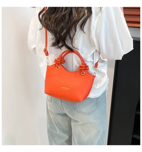 Close-up of orange bucket bag featuring unique knotted handle and lychee texture