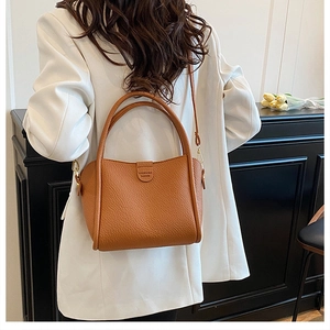 Close-up of brown pebbled leather basket bag styled with a white blazer for a chic look
