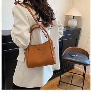 Brown lychee textured leather tote bag shown on a model in a minimalist home setting