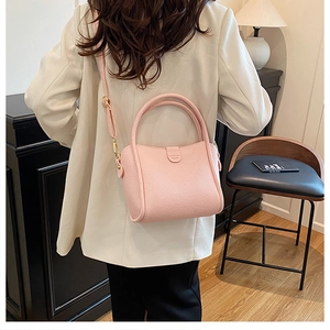 Rear view of a model wearing a pink lychee grain leather bucket bag in a warm room