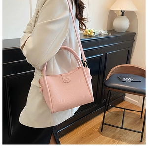 Pink lychee grain leather handbag detail showing texture and adjustable strap design