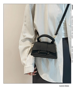 Close-up of black woven texture mini handbag with metal ring buckle and wide top handle