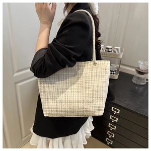 Détail d'un sac cabas en tweed beige avec des poignées en corde tressée à l'épaule