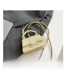 Detailed close-up of straw woven texture and adjustable strap on mini beige handbag