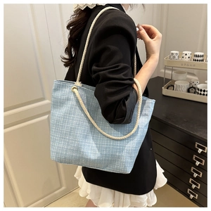 Vue latérale du grand sac cabas en tweed bleu clair avec anses en corde sur l'épaule