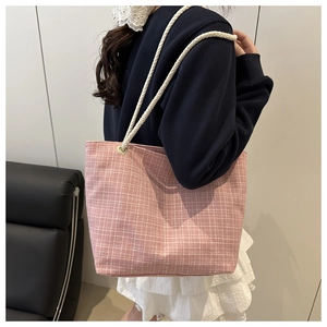 Détail du sac cabas en toile à carreaux roses avec anses en corde de coton porté à l'épaule
