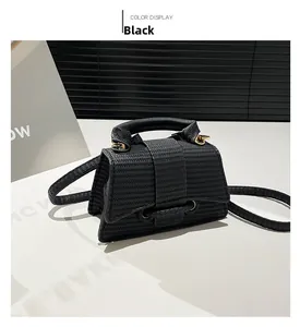 Detail of black mini square bag featuring woven texture and golden ring metal hardware